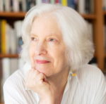 Portrait of Judith Shatin seated in front of bookshelf